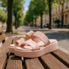 Ροζ flatforms πάνω σε ξύλινο παγκάκι σε δεντροφυτεμένο πεζόδρομο.
